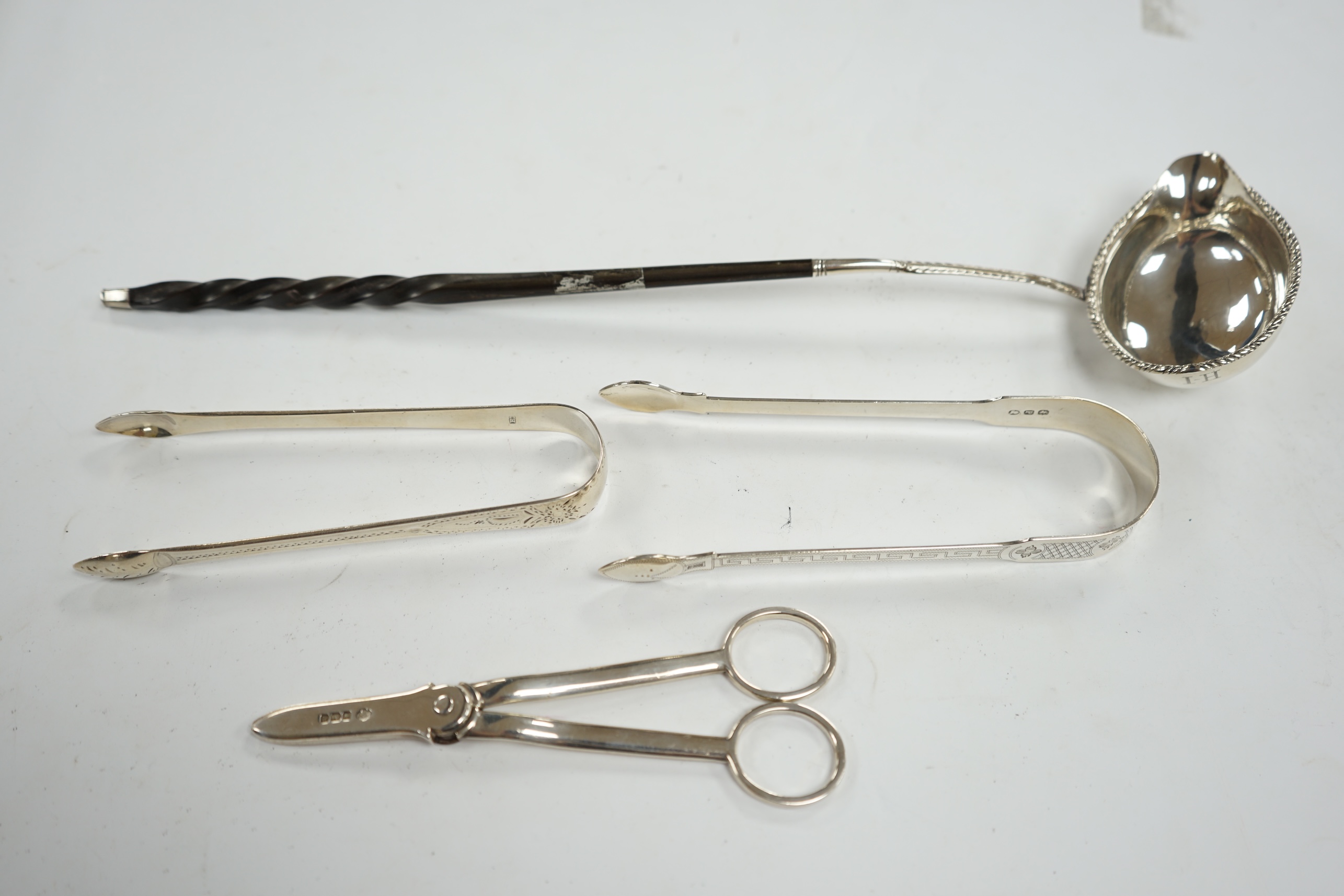 A pair of George V silver grape scissors, by William Hutton & Sons, two pairs of silver sugar tongs and a Georgian silver punch ladle. Condition - poor to fair